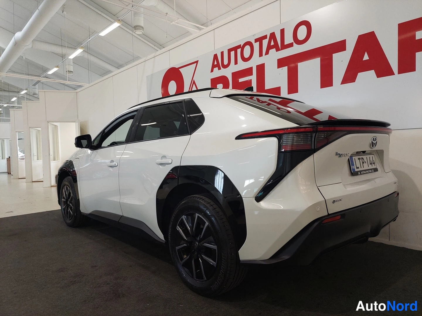 Takaviisto: Valkoisen Toyota bZ4X:n takakulmakuva sisätiloissa, rekisterikilpi näkyvissä.