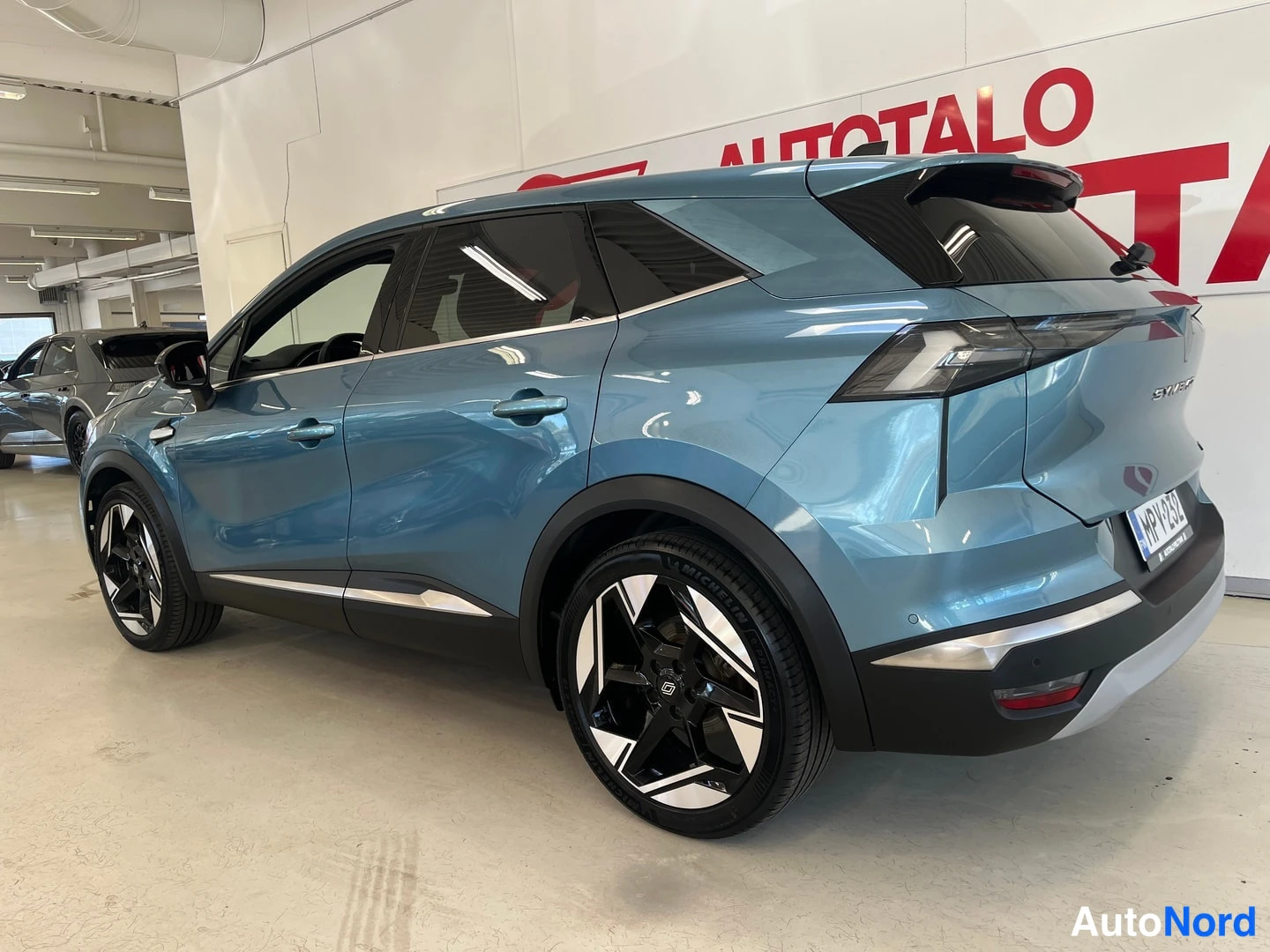 Takaviisto: Sinertävänharmaa Renault Symbioz -maastocoupé takaviistosta sisätiloissa, rekisterikilpi näkyvissä.