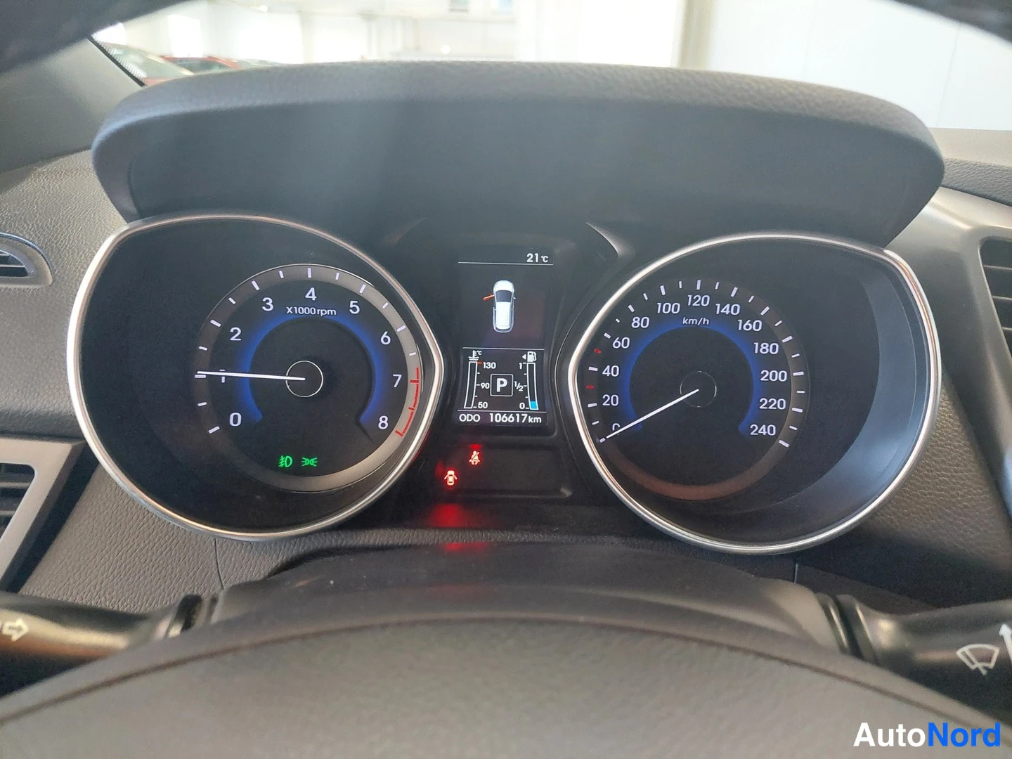 Muu: Hyundai i30:n mittaristo: kierroslukumittari ja nopeusmittari 0–240 km/h, keskellä P-vaihde ja lukema ODO 106617 km; lämpötila 21 °C.
