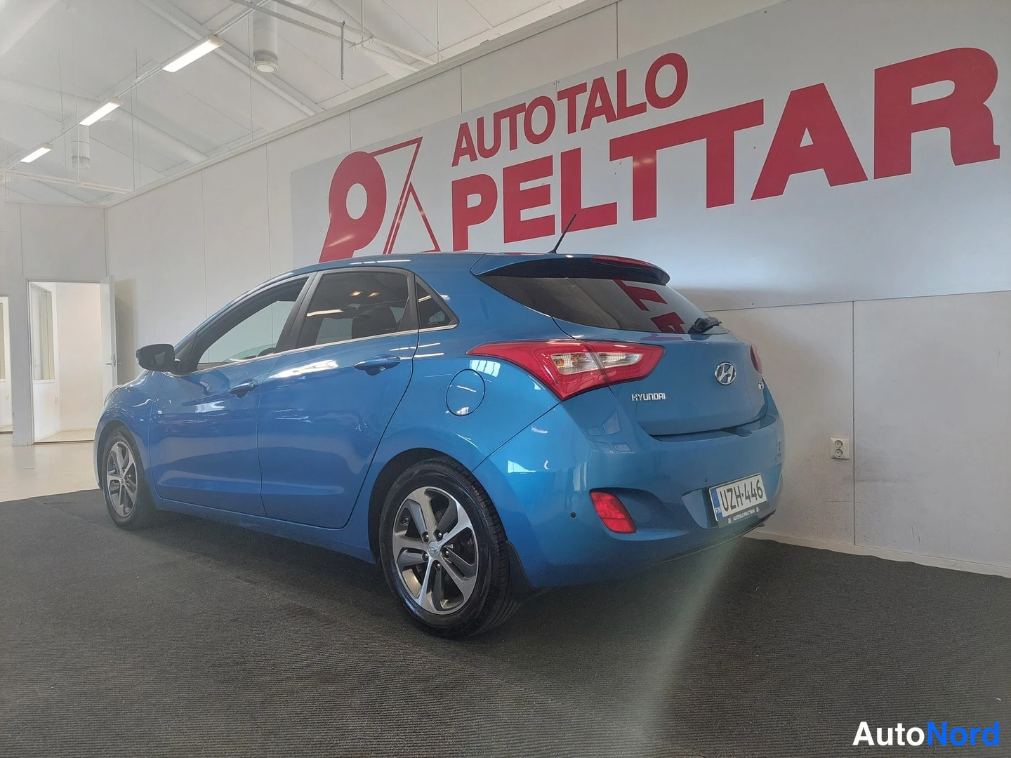 Takaviisto: Sininen Hyundai -henkilöauto kuvattu takaa viistosti oikealta, rekisterikilpi, takavalo ja HYUNDAI-merkki näkyvissä.