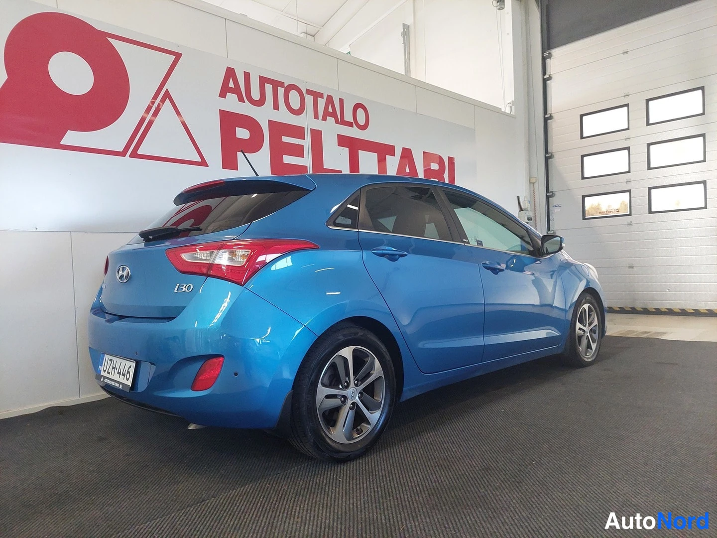 Takaviisto: Sininen Hyundai i30 takaviistosta vasemmalle, takaosa ja vasen sivu näkyvissä.