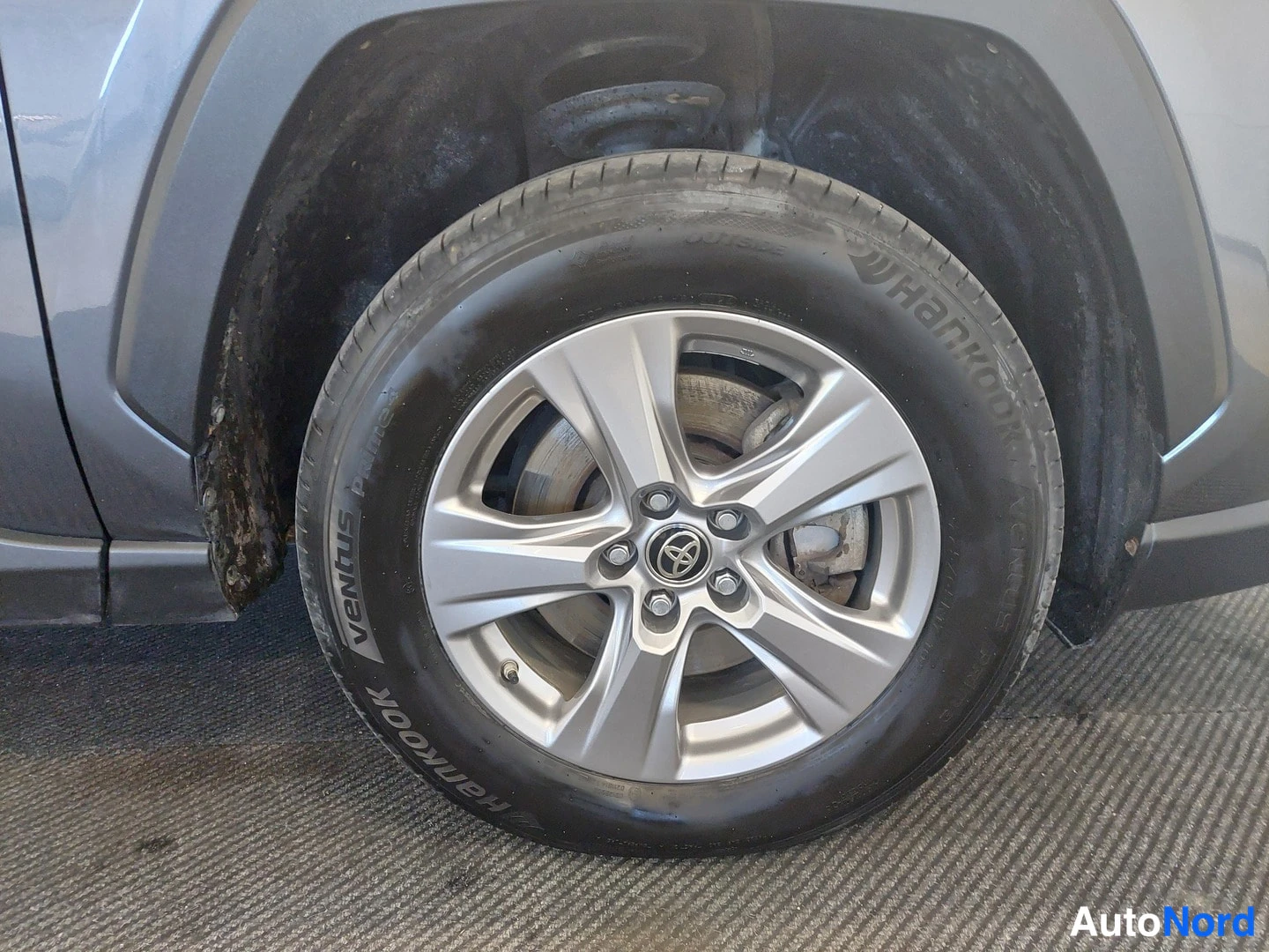 Sivulta: Auton pyörän lähikuva: hopeavanteella varustettu Hankook Ventus -kesärengas, jarrulevy ja Toyota-merkitty keskusnuppi näkyvät.