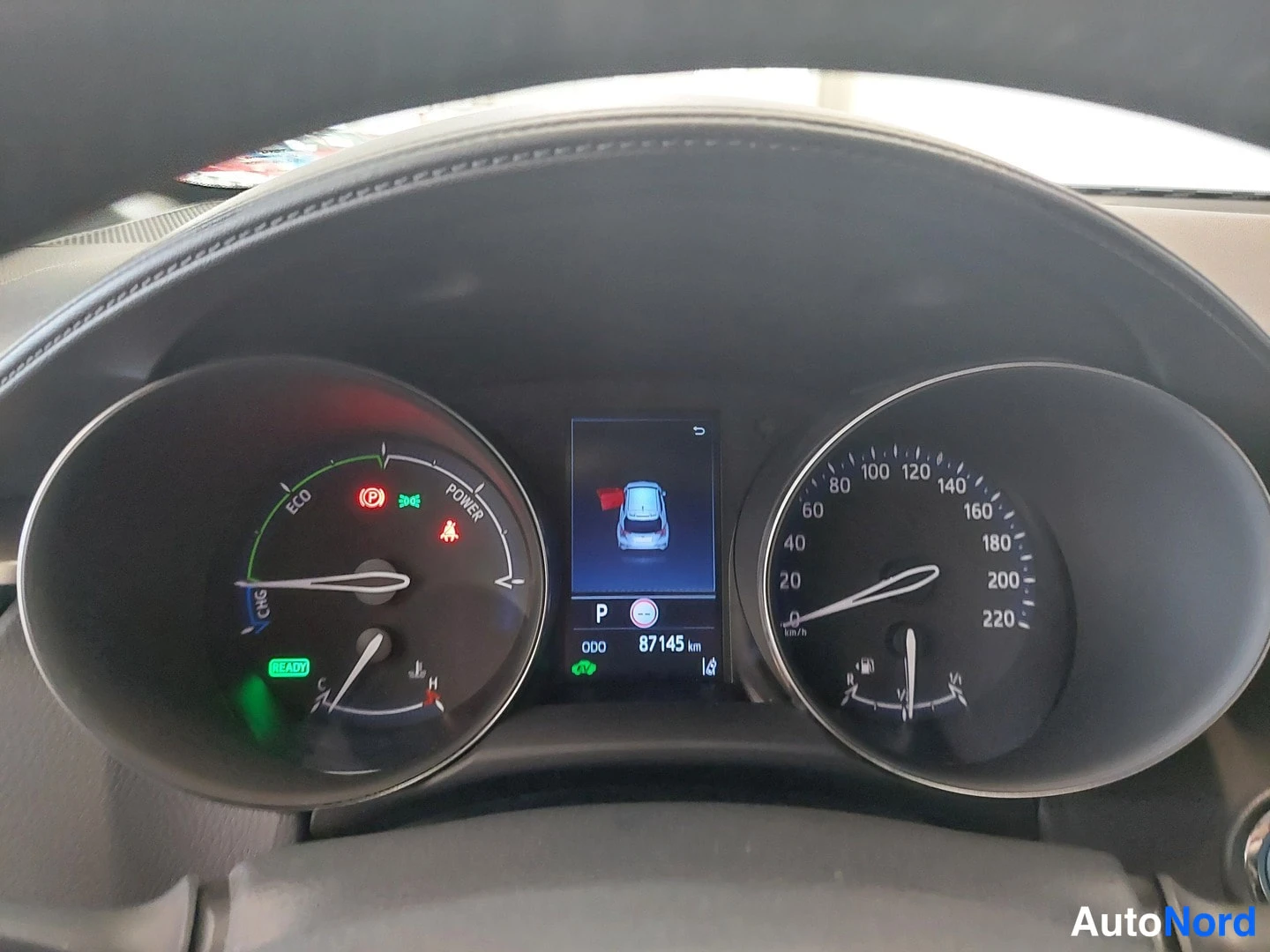 Muu: Mittariston lähikuva: hybridimittarit ja keskinäyttö näyttävät odometerilukeman 87145 km ja vaihteen P.