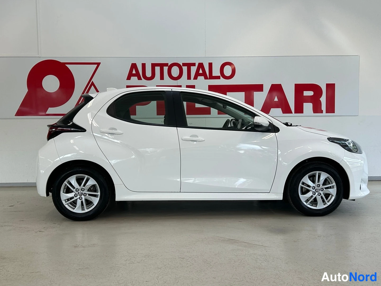 Sivulta: Valkoinen Toyota Yaris kyljestä suoraan kuvattuna.
