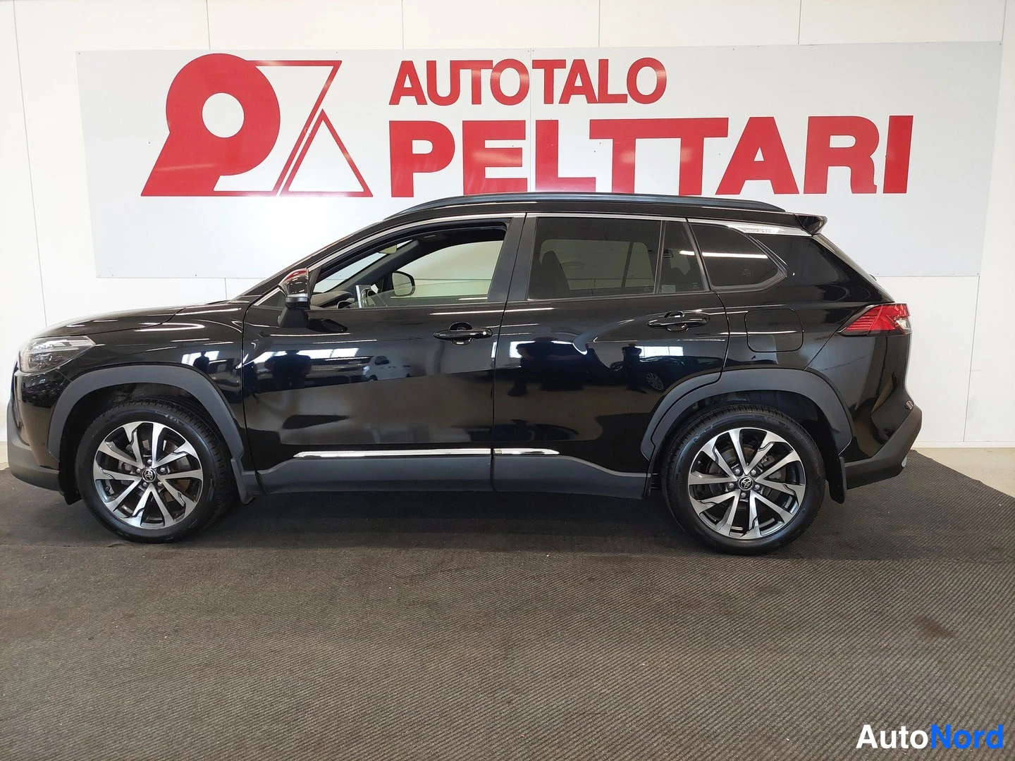 Sivulta: Mustan Toyota Corolla Crossin sivukuva sisätiloissa.