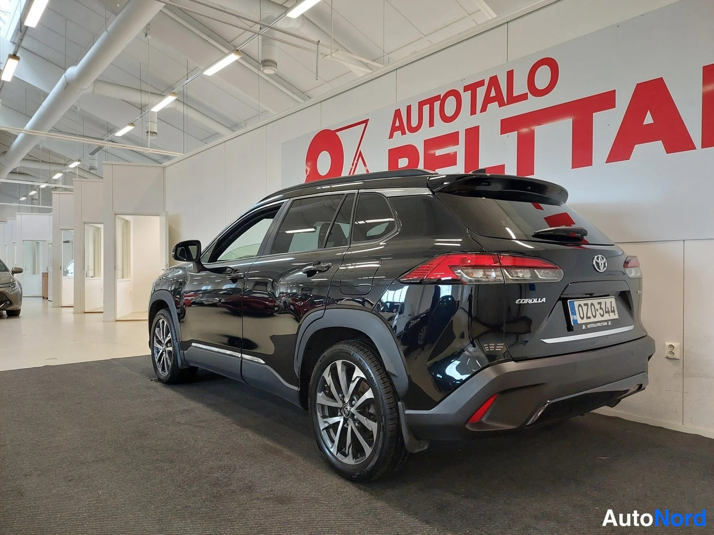 Takaviisto: Mustan Toyota Corolla Crossin takalapanokuva sisätiloissa, rekisterikilpi.
