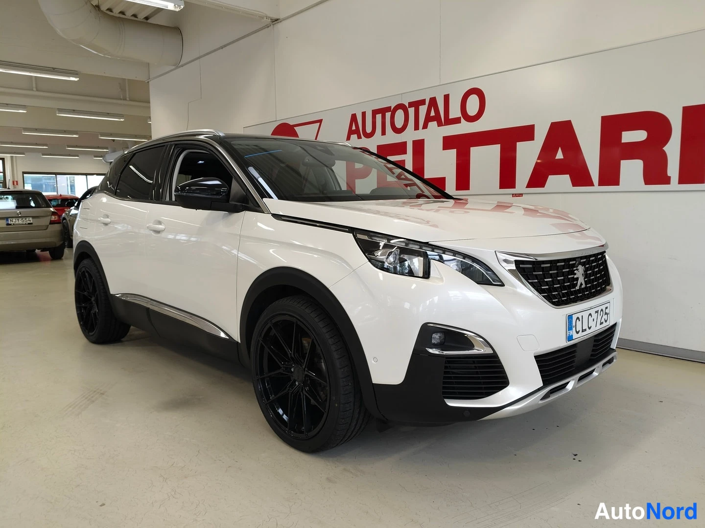 Etuviisto, nokka oikealle: Etukulmanäkymä valkoisesta Peugeot 3008:sta, etusäleikkö ja Peugeot-logotyyli, mustat kevytmetallivanteet ja rekisteritunnus näkyvät.