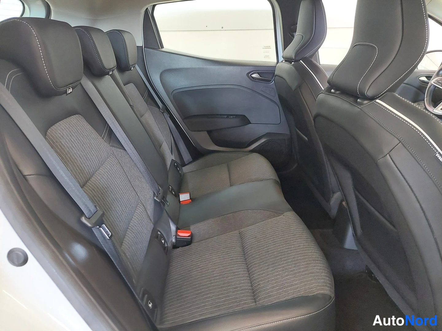 Muu: Auton takapenkin ja sisätilojen kuva: mustat kangasverhoillut istuimet ja mustat ovet.