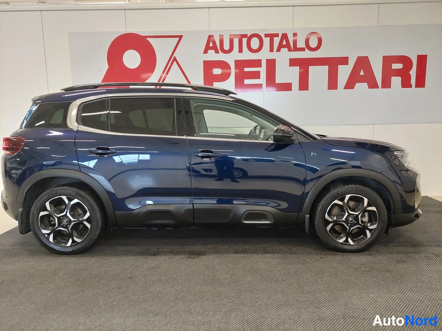 Etuviisto, nokka oikealle: Sivukuva tummansinisestä Citroën C5 Aircross -automobilista, kattokaiteella ja kevytmetallivanteilla.