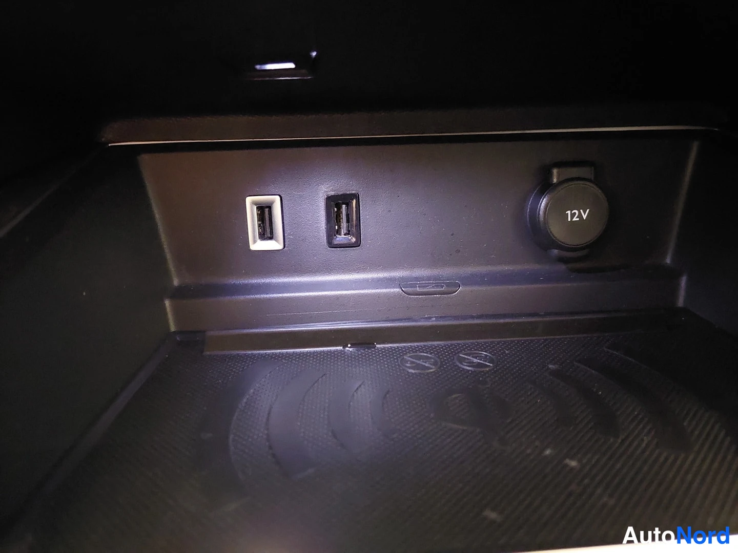Yksityiskohta: Keskikonsolin alapöytä: kaksi USB-porttia ja 12 V -virtalähde, alla langattoman latauksen matto.