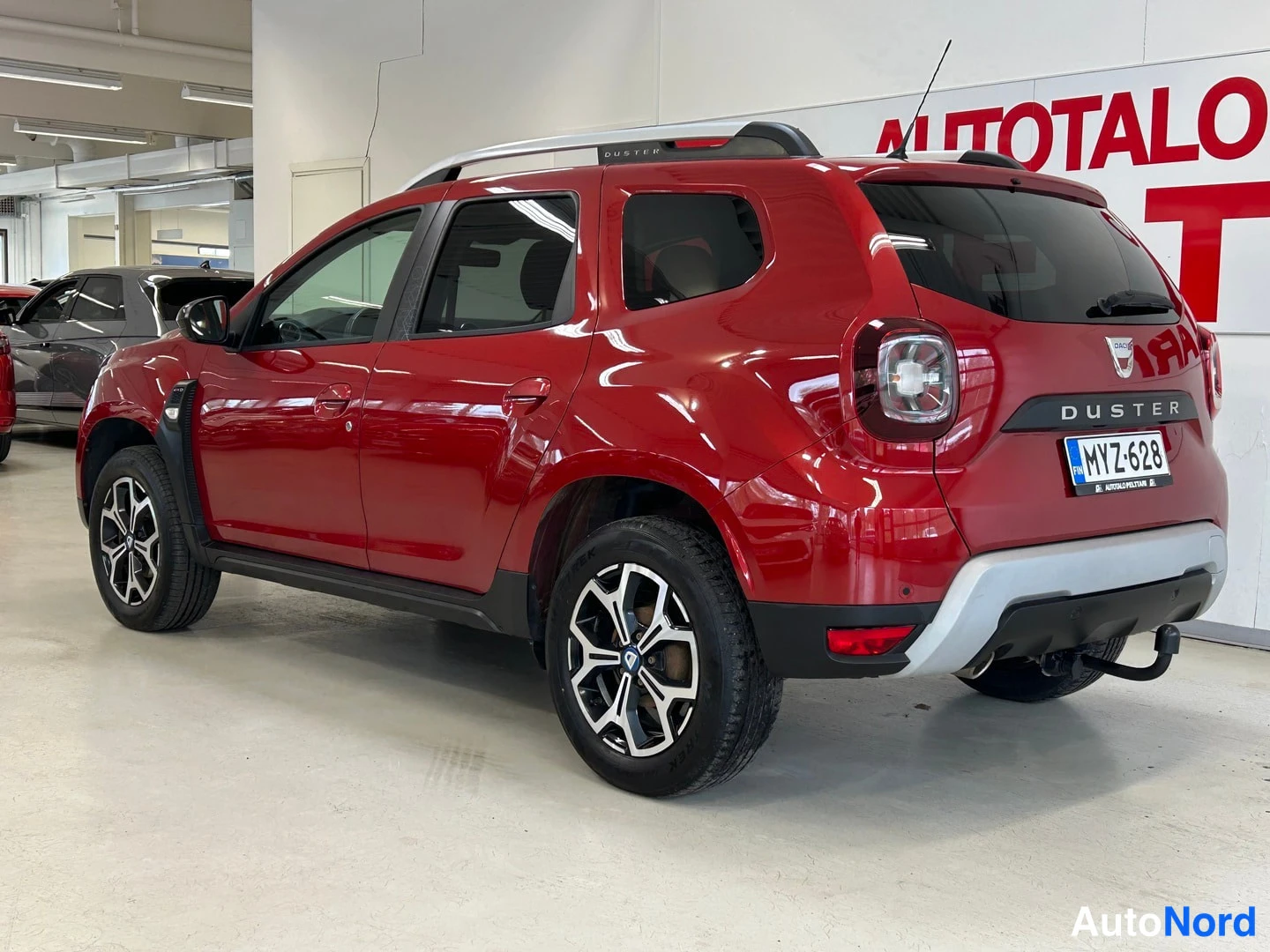 Takaviisto: Punainen Dacia Duster kuvattu takaa vasemmalta, rekisterikilpi ja DUSTER-teksti näkyvissä.