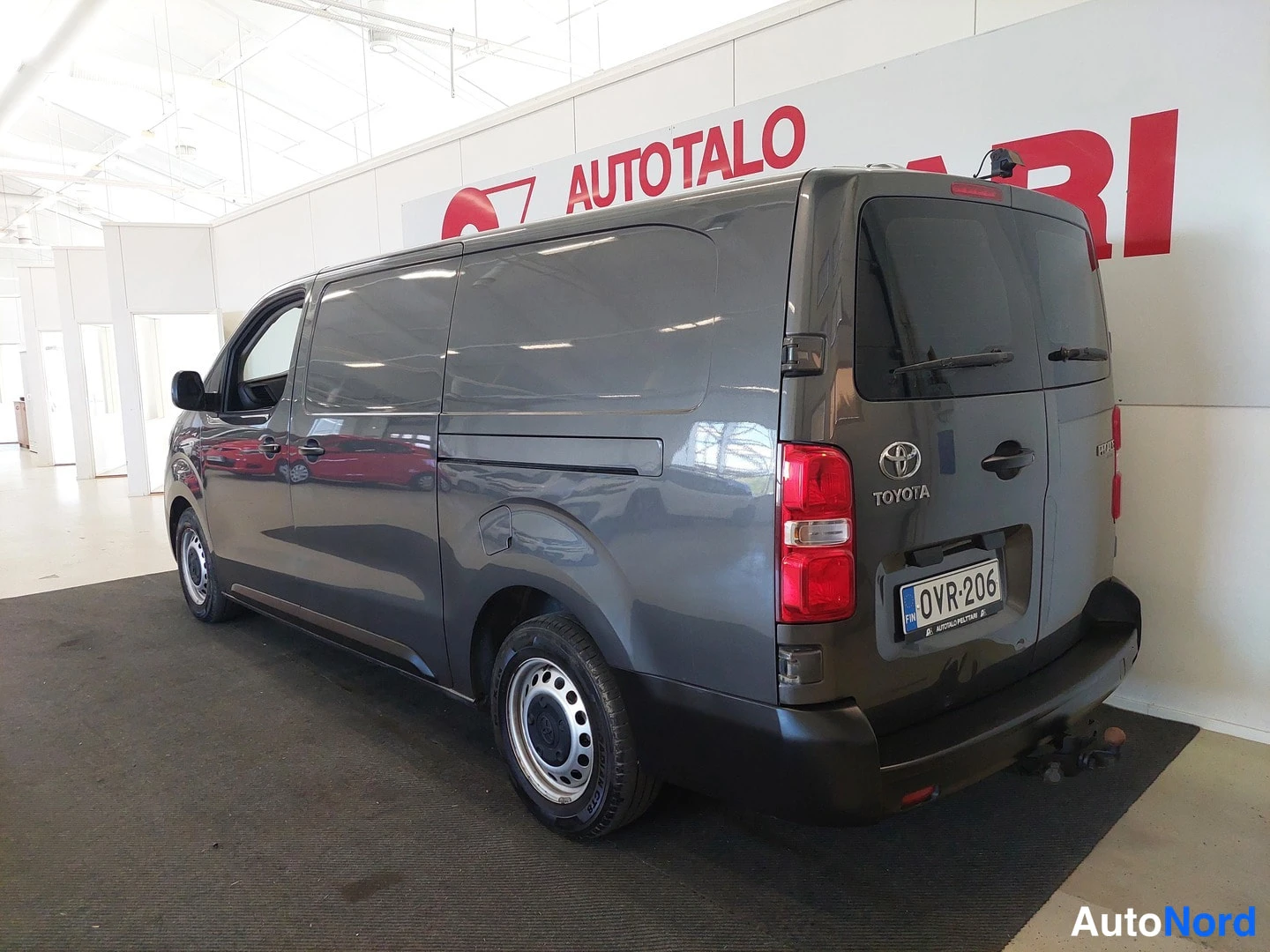 Takaviisto: Tummanharmaan Toyota Proace -pakettiauton takapää ja vasen kylki kolmesta neljäsosasta; Toyota-merkki, takavalot ja rekisterikilpi näkyvät.