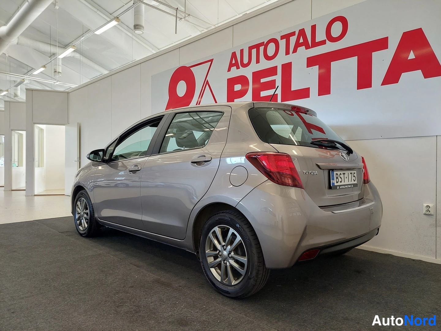 Takaviisto: Toyota Yaris -henkilöauton takanurkkakuva sisätiloissa; rekisterikilpi näkyvissä.
