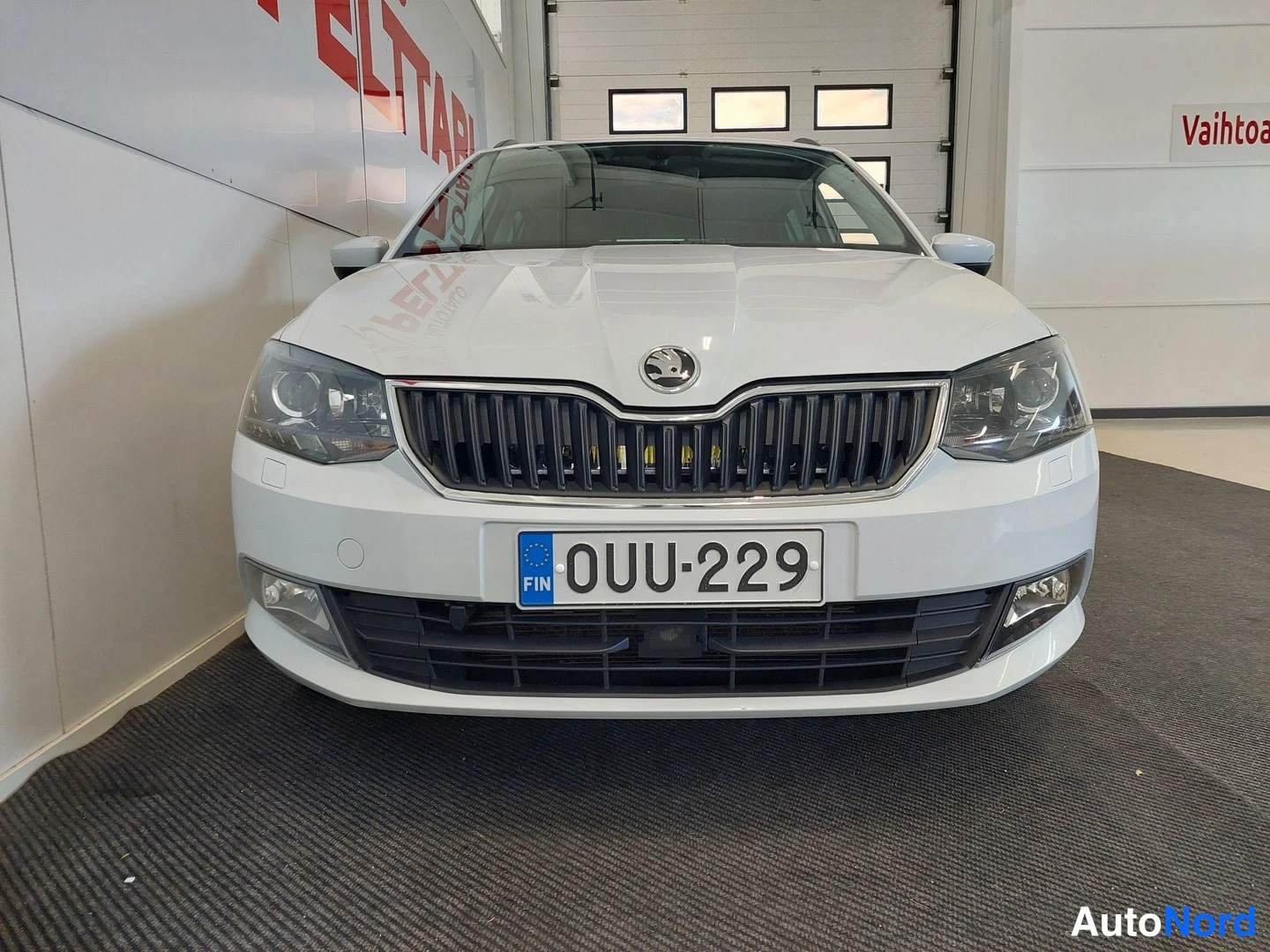 Edestä: Skoda Fabia Combi etusivulta, valkoinen, rekisteritunnus, valoja ja etusumuvalot näkyvissä.