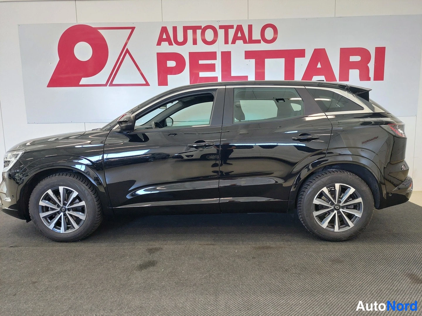Etuviisto, nokka vasemmalle: Musta Renault Austral -henkinen farmarimallinen SUV sivulta etukulmasta, etuosa vasemmalla.