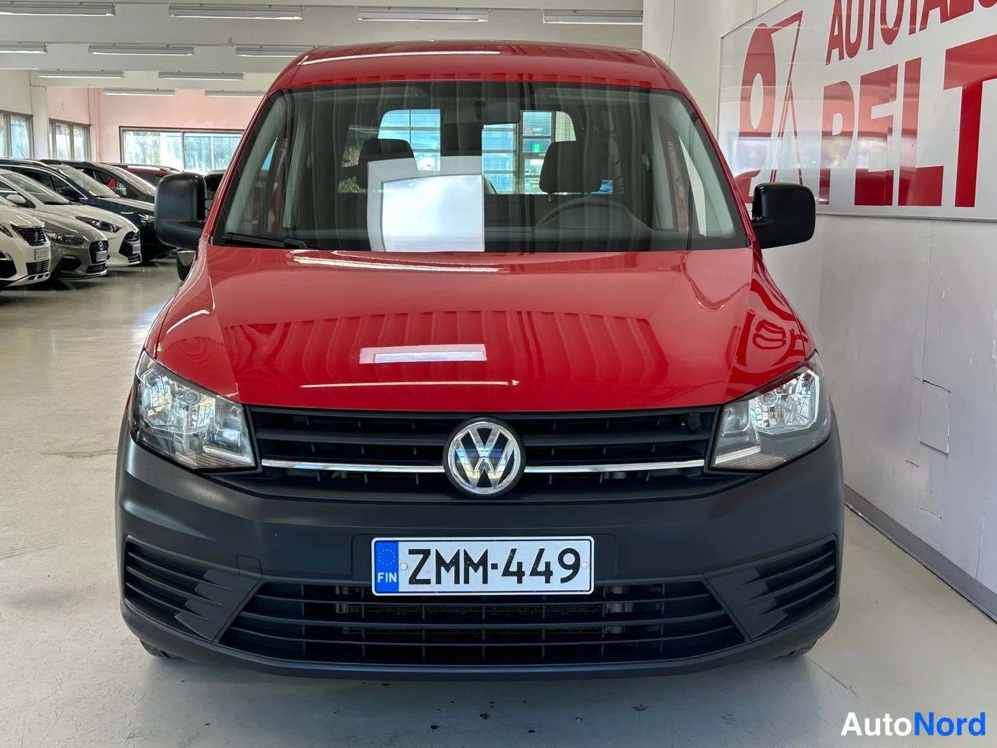 Edestä: Punaisen pakettiauton keulakuva, VW-merkki ja rekisteritunnus