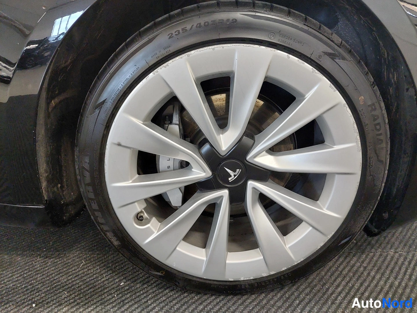 Yksityiskohta: Lähikuva mustan auton pyörästä: hopea aerodynamiikkavannas, rengassivussa merkintä 235/40ZR19 ja Michelin-tunnus.