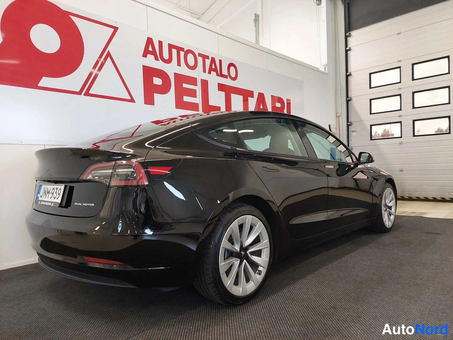 Takaviisto: Mustan sedanin takaosa kolmanneskulmasta sisätiloissa: takavalot, -rekisterikilpi ja DUAL MOTOR-teksti takaluukussa, hopeiset peltivanteet.