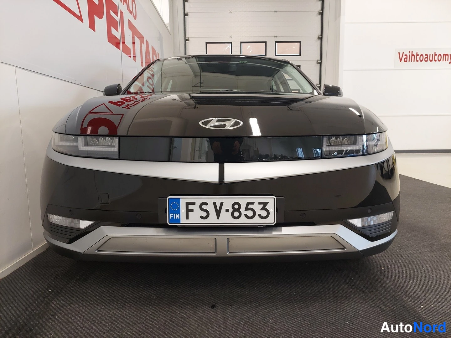 Edestä: Hyundai IONIQ 5:n etupää edestäpäin kuvattuna sisätiloissa, rekisterikilpi.