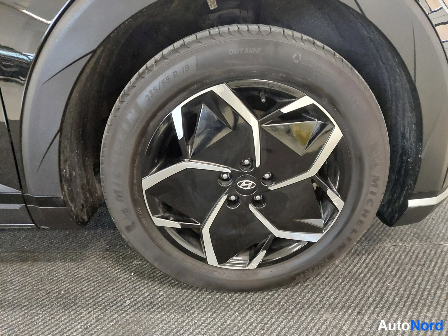 Muu: Lähikuva mustasta kevytmetallivanteesta Hyundai-logolla ja Michelin-renkaasta, jonka sivussa lukee 235/55 R 19.