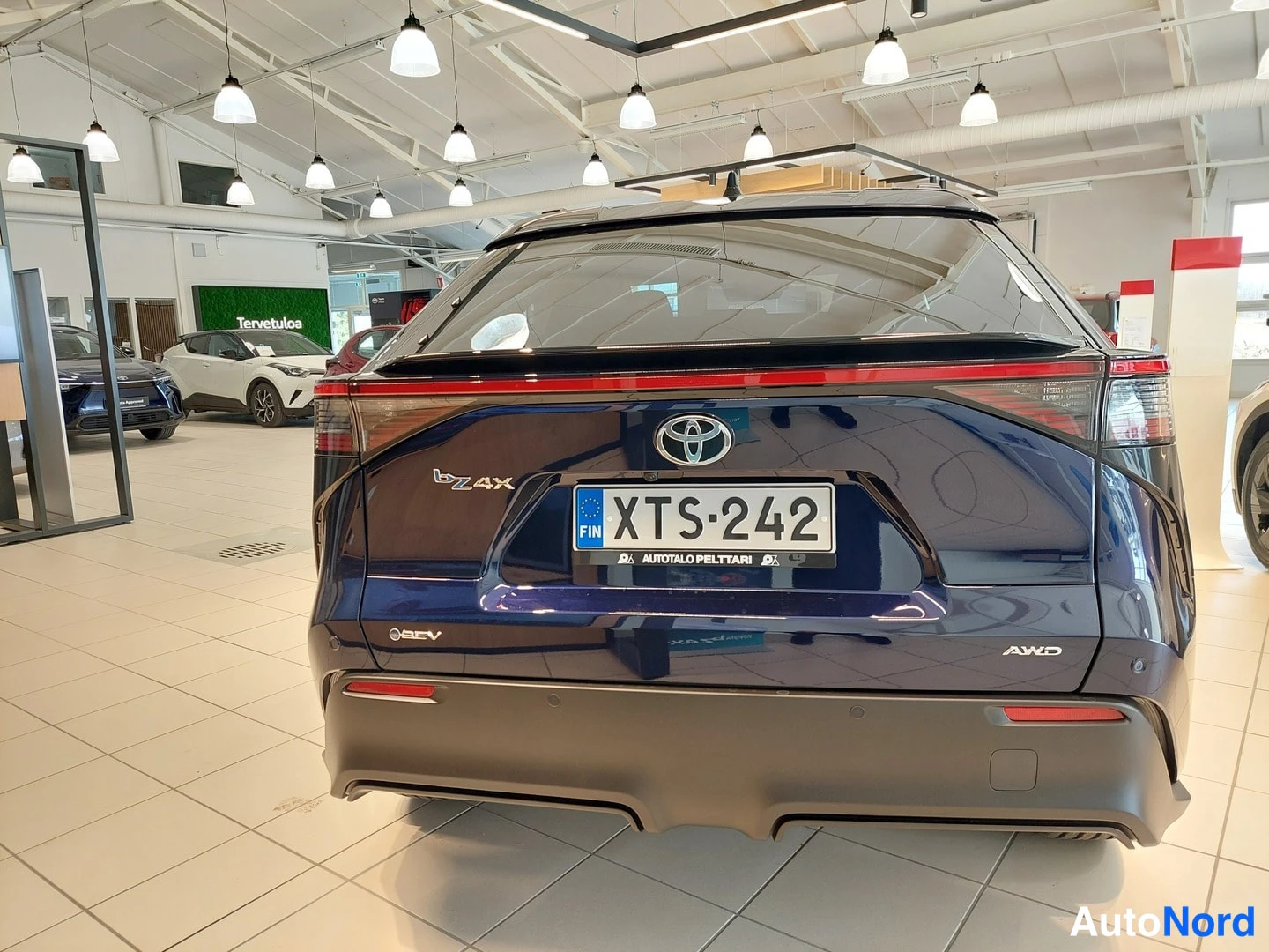 Takaa: Sinisen Toyota bZ4X:n takaosa huoltamossa, rekisterikilpi.