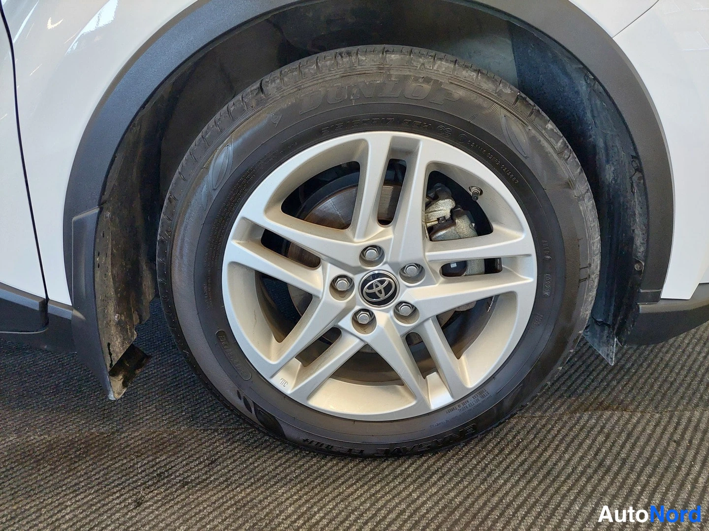 Muu: Valkoisen auton etupyörä, hopeinen alumiinivanne ja Toyota-logo pölykotelossa.