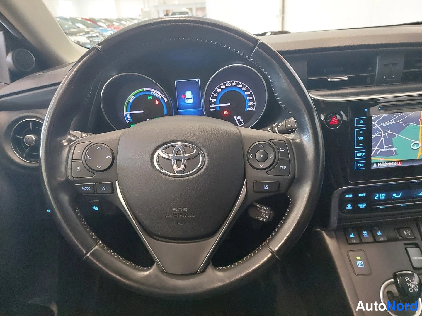 Etuviisto: Toyota-merkkinen ohjauspyörä, hybridin mittaristo ja kosketusnäytöllinen aitio.