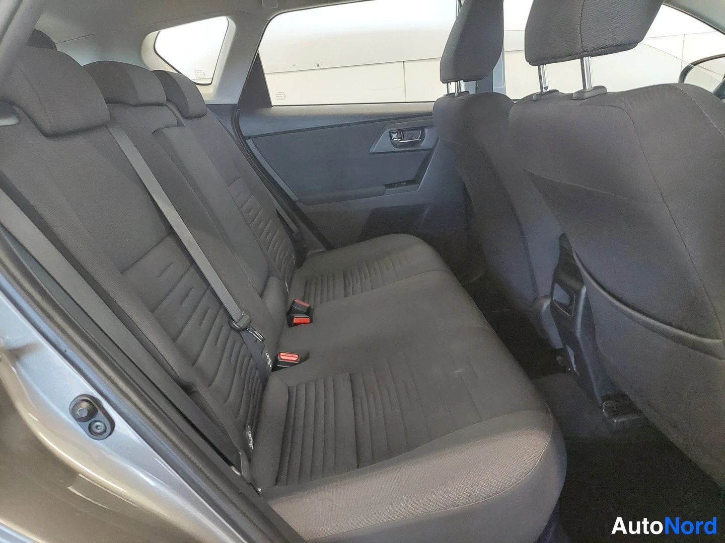 Yksityiskohta: auton takaistuin, tummaa kangasta, kolme headrestia ja kaksivärinen verhoilu