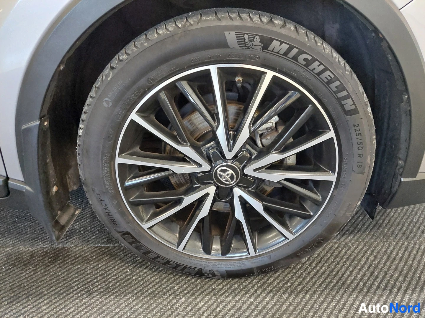 Sivulta: Toyota C-HR -yksityiskohtakuva: taka- tai etupyörä sulkuluukkuineen, kaksivärinen alloy-vanne ja Michelin-talvirengas.