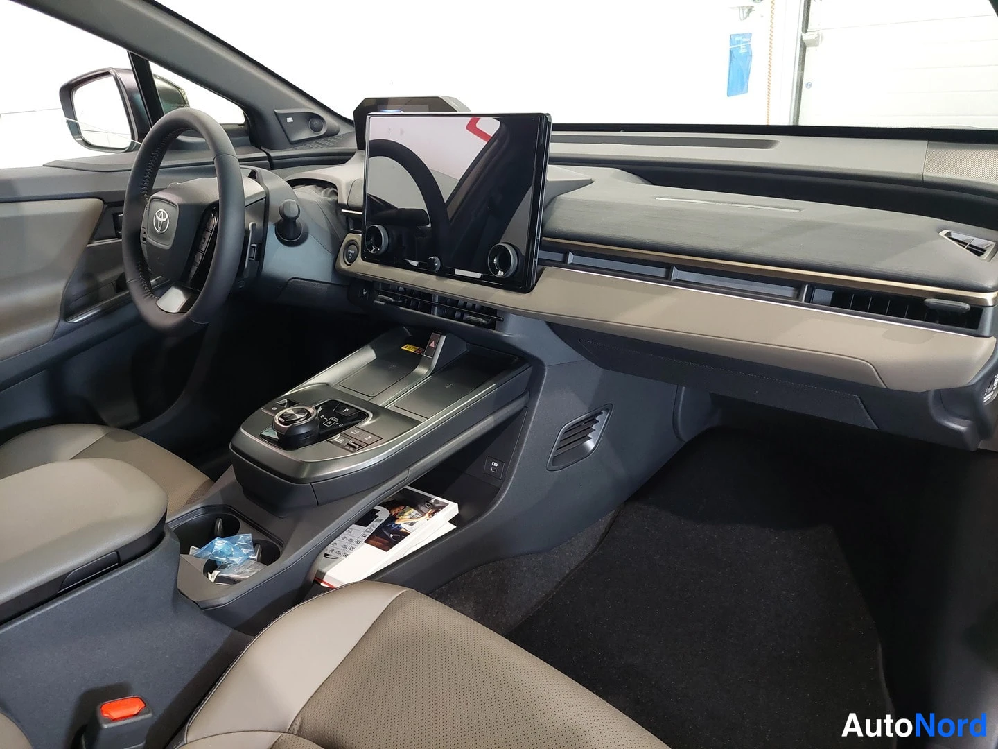 Muu: Auton sisätilan yleiskuva: Toyota-merkkinen ohjauspyörä, iso vaakasuuntainen infotainment-näyttö keskellä kojelautaa, Aalloukseiset etupenkit ja keskitunnelin s