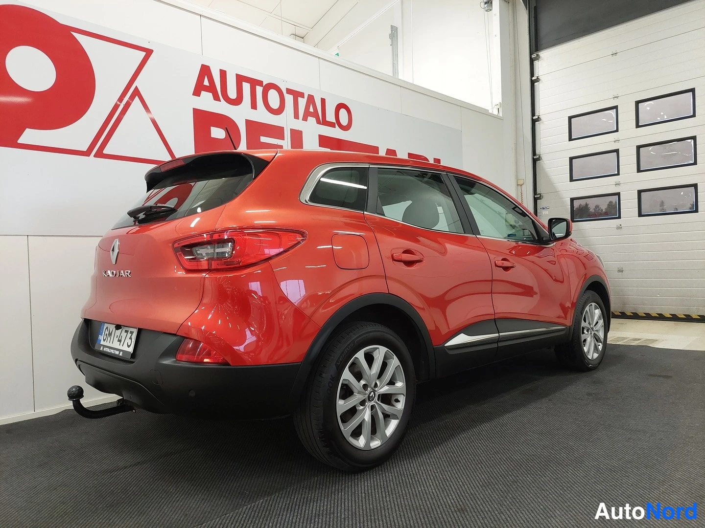 Takaviisto: Punaisen Renault Kadjarin takaosa ja vasen sivu kolmesta neljäsosaan, KADJAR-merkintä takaluukussa ja vetoaisa takapuskurissa.