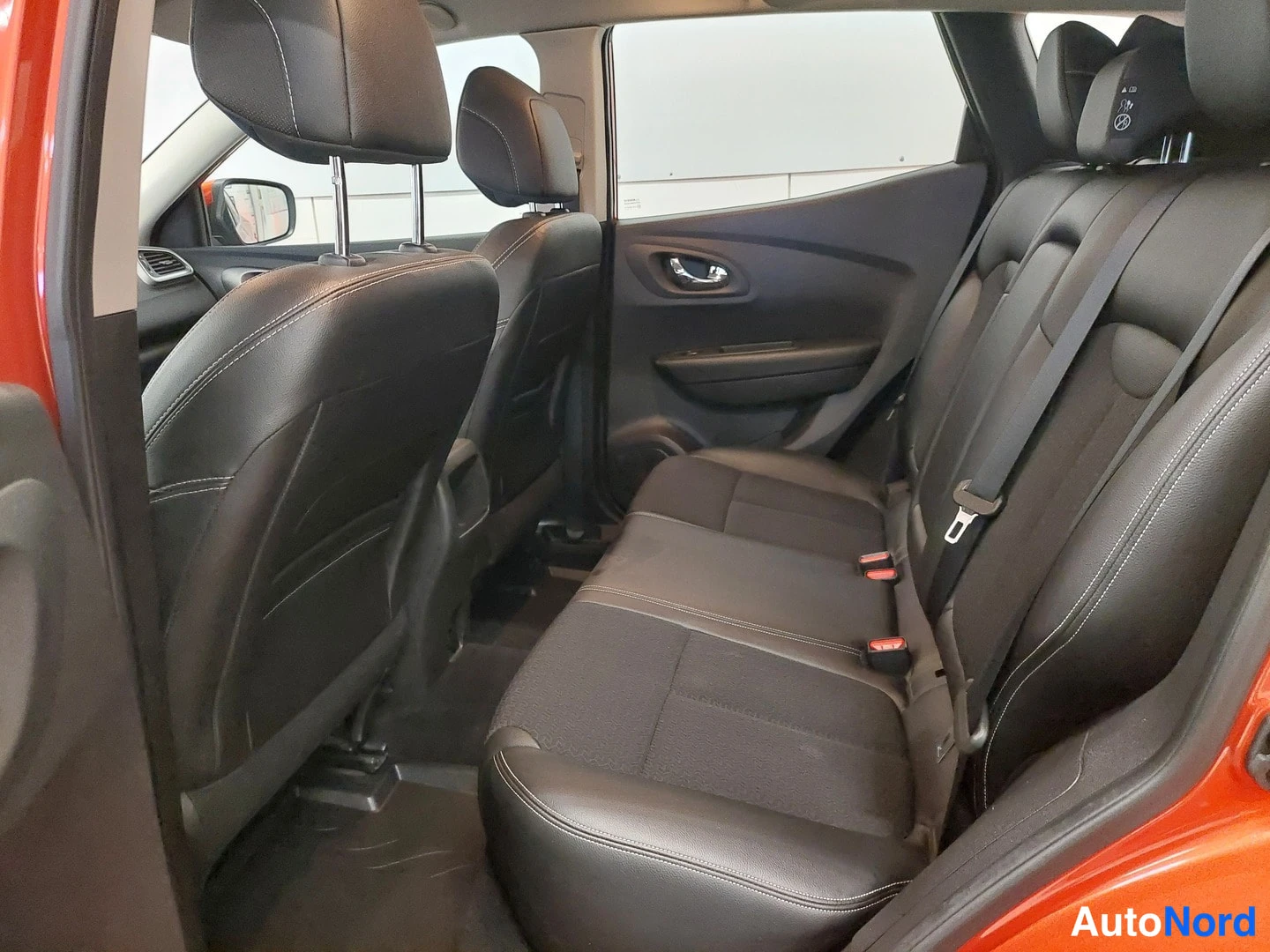 Muu: Renault Kadjar 2017 – takaistuin ja takaosan matkustamo: tummat istuimet, avoinna oleva takaoveen aukko, punertava koripaneeli reunoilla.