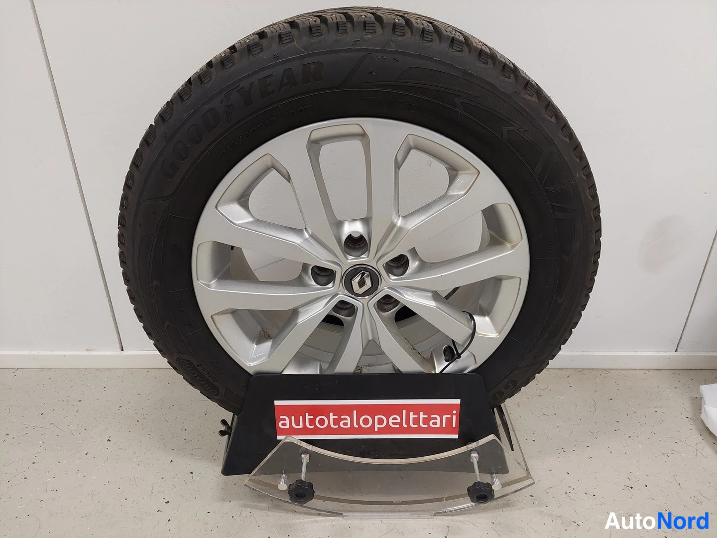Muu: Goodyear-talvirenkainen auton pyörä hopeisella Renault-kevytmetallivanteella mukana toimituspohjassa, jonka kyljessä lukee autotalopelttari.