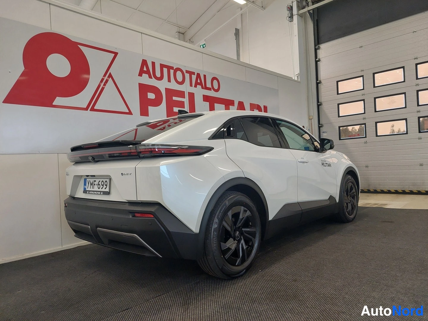 Takaviisto: Valkoisen Toyota C-HR:n takakolmannes autotallin sisällä, rekisteritunnus.