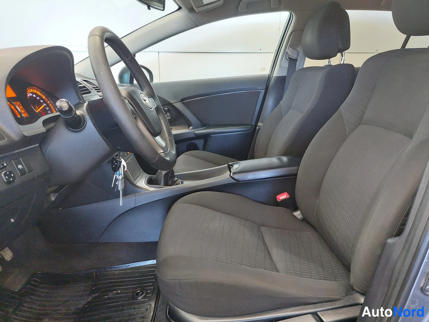 Muu: Etumatkustustila sivulta: Toyota-ohjauspyörä, tummat kankaanistuimet ja keskikonsolin käsinoja.