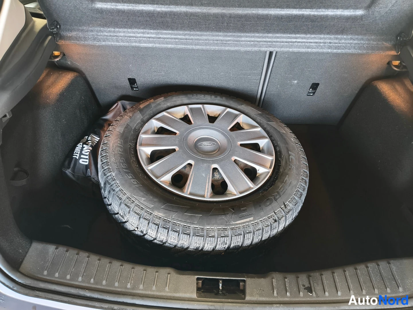 Muu: Tavaratila, jossa vararengas Pirelli-rengas ja Ford-pölykotelot tavaratilan pohjalla.