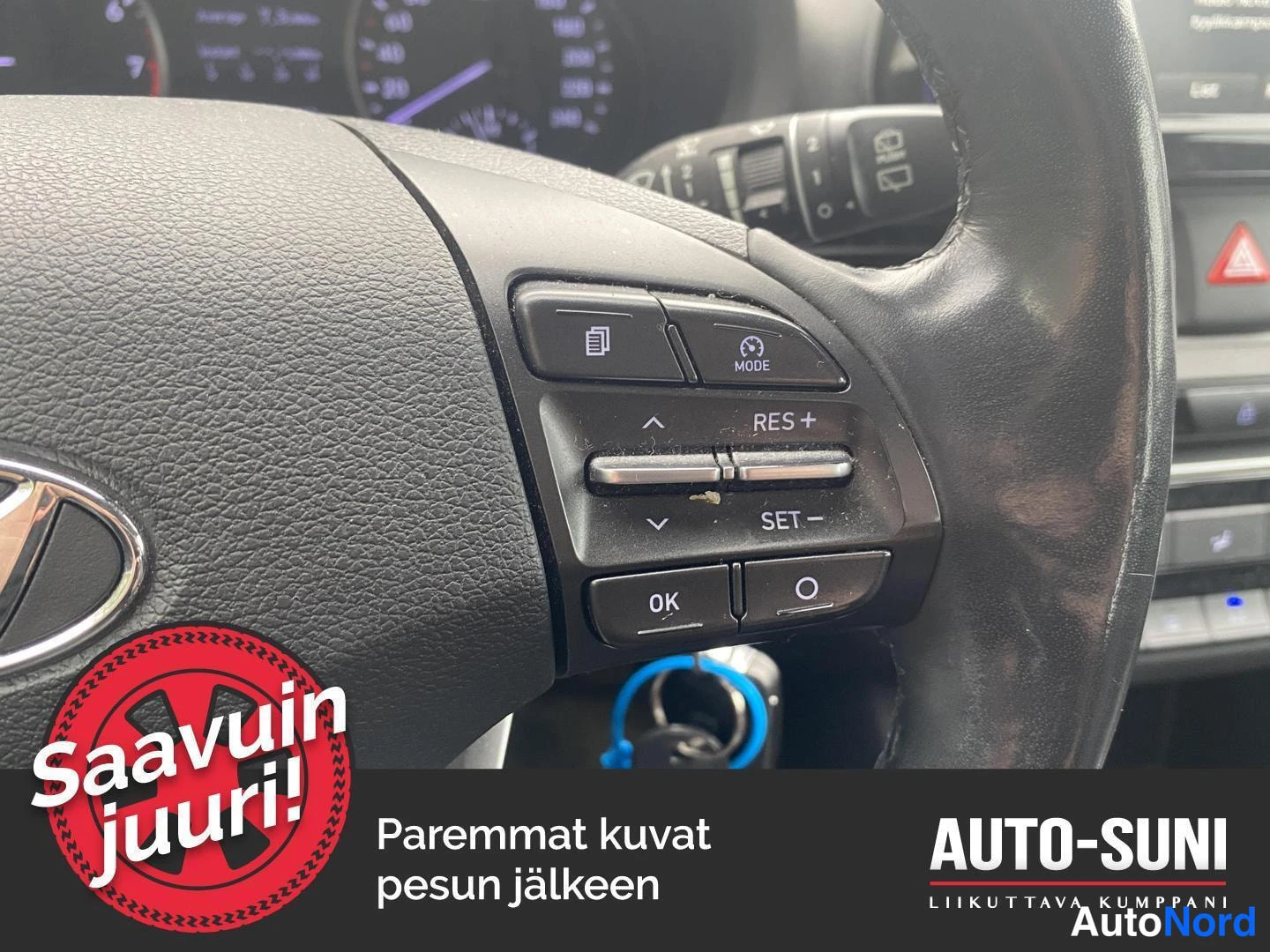 Yksityiskohta: Hyundai-pyörän ohjauspyörän nappien lähikuva: risteystoiminnot, RES+ ja SET- painikkeet sekä Mode-nappi; mittaristo ja avain näkyvät taustalla.