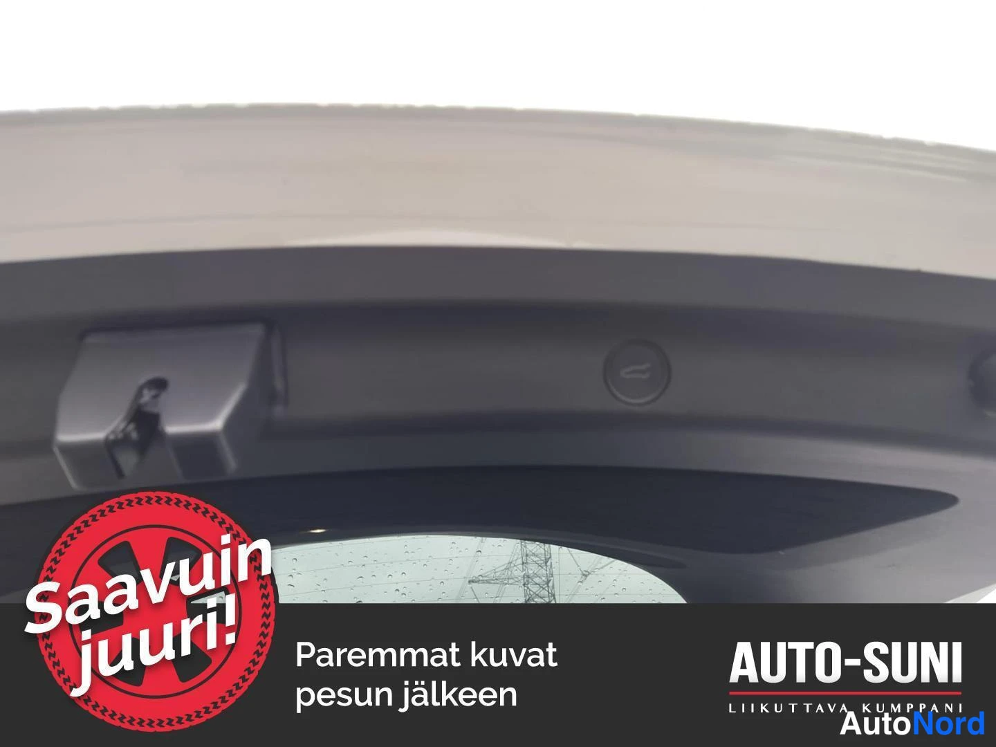 Yksityiskohta: Yksityiskohtainen kuva avatun takaluukun sisäpinnasta, tumma runko ja taustapeili aukon läpi.