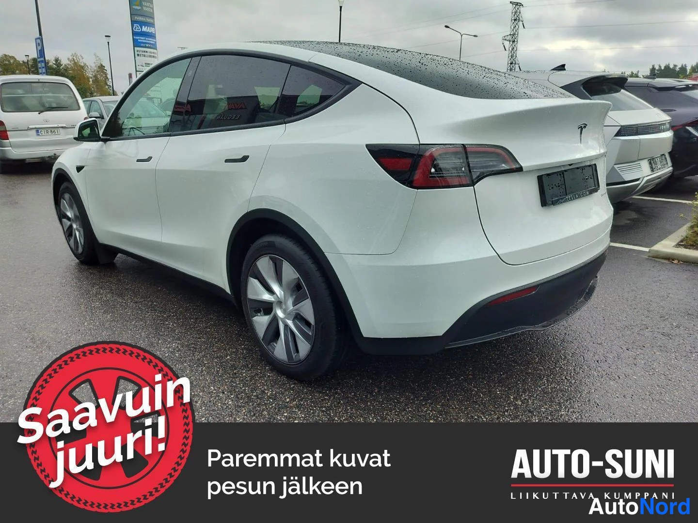 Takaviisto: Valkoinen Tesla Model Y taka-3/4-kulmakuva, keula vasemmalla, takavalot ja lastauskansi näkyvissä.