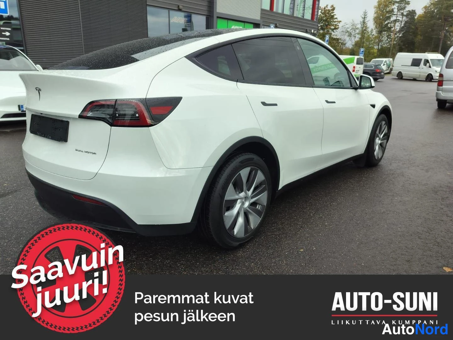 Takaviisto: Valkoinen crossover kolmannesnäkymä takaa: tummat ikkunat, hopeaharmaat vanteet, takavalot ja Dual Motor -teksti bootissa.