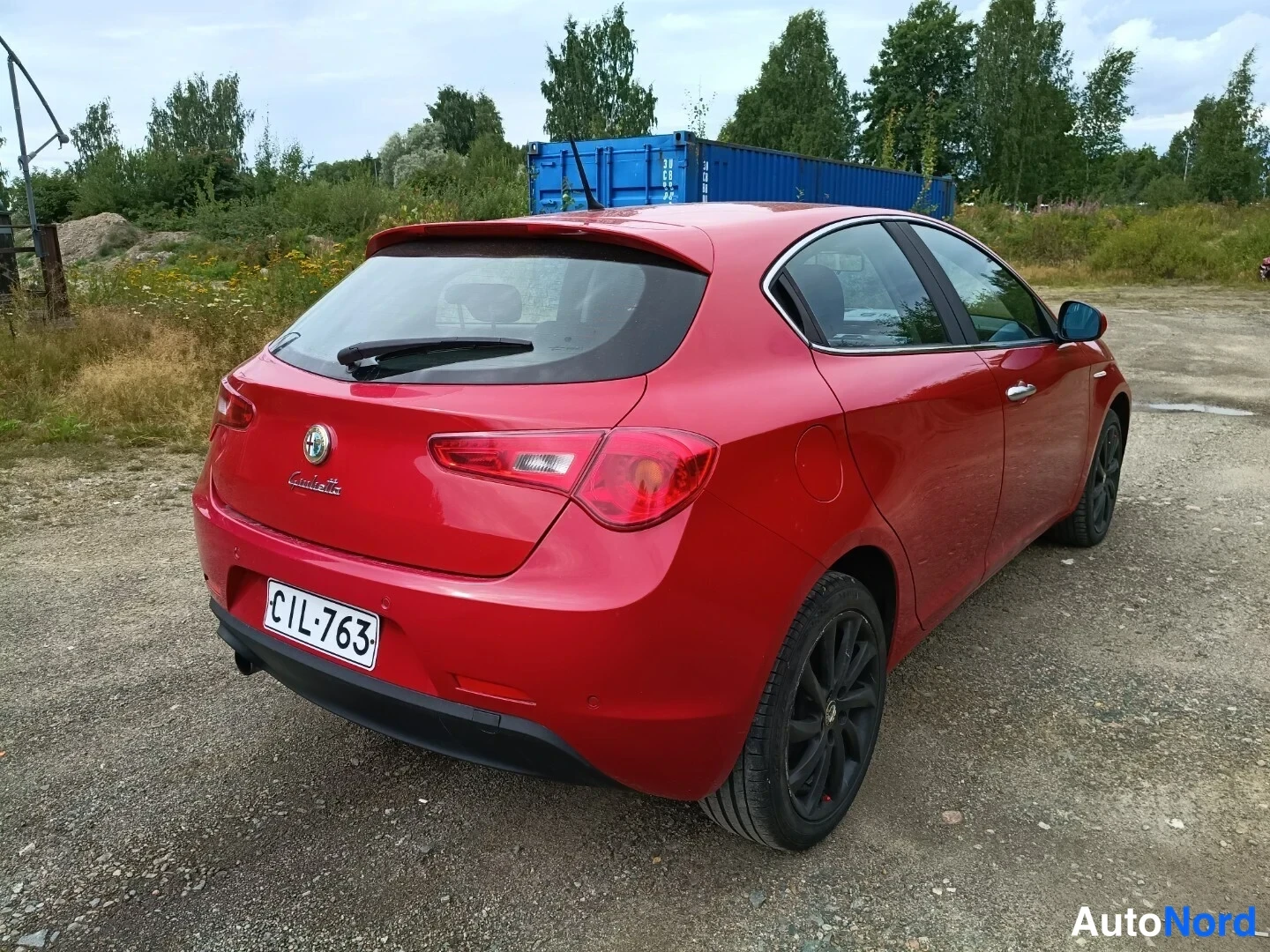 Takaviisto: Punaisen Alfa Romeo Giuliettan takakolmatsossa rekisteritunnuksella, takanapa ja mustat vanteet.