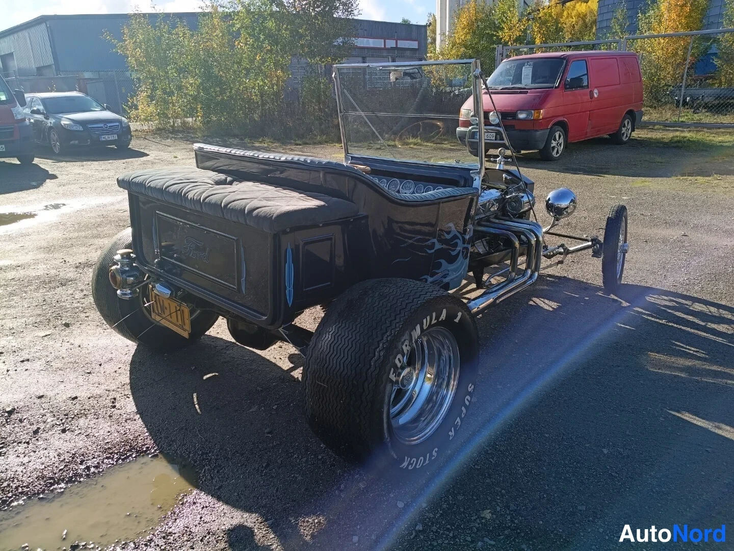 Takaviisto: Mustan avoimen hot rodin takaosa ja oikea kylki kuvassa; takalava, keltainen rekisterikilpi ja leveä takarenkaita.
