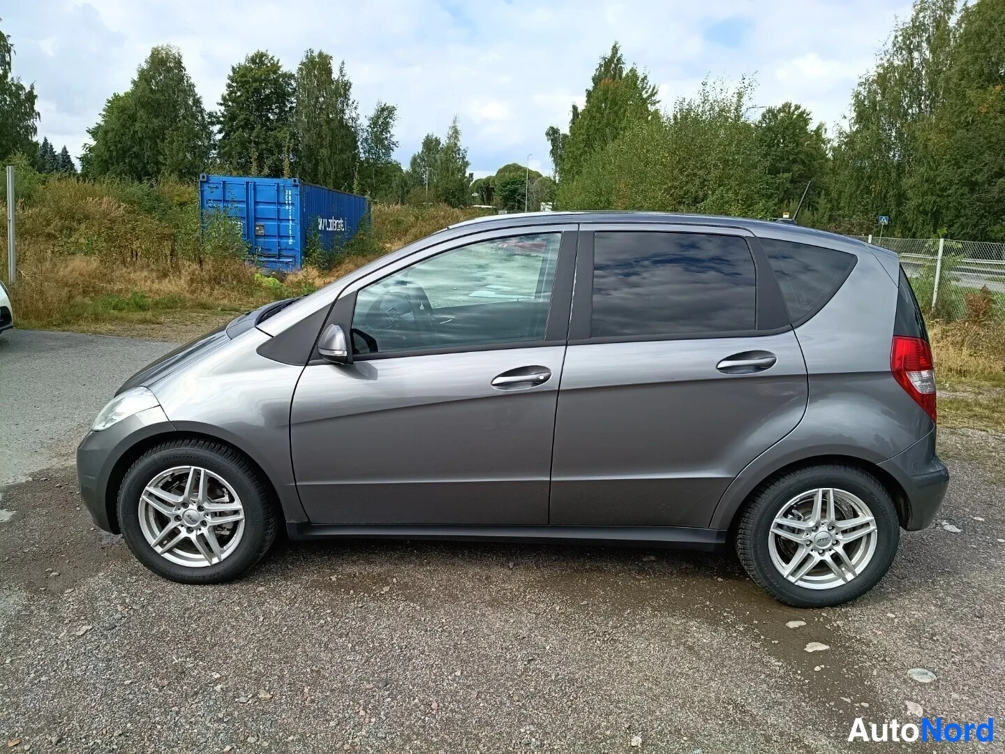 Sivulta: Mercedes-Benz A:n sivukuva oikealta puolelta harmaana avoimella parkkipaikalla.