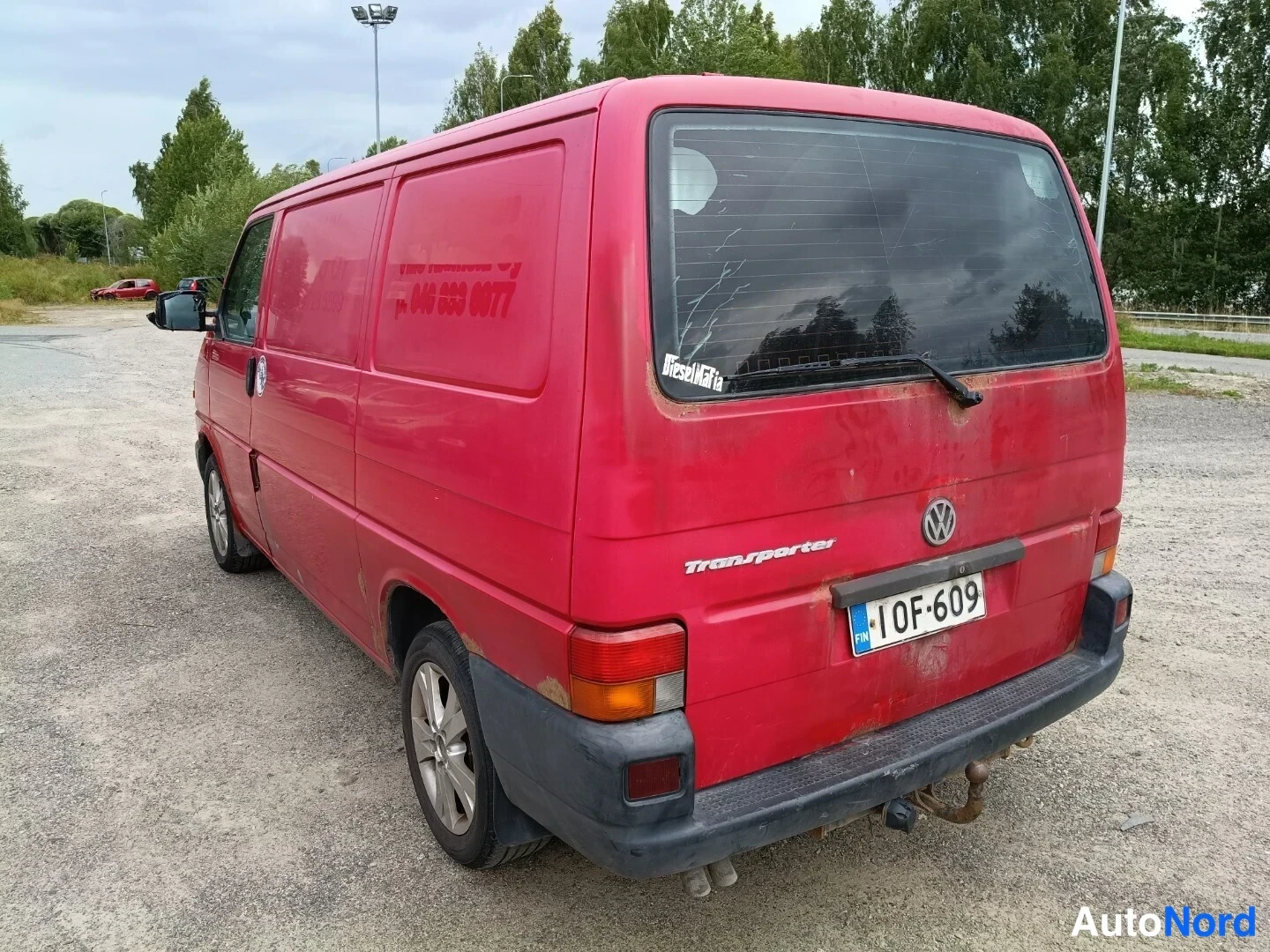 Takaviisto: Punainen Volkswagen Transporter takakulmasta, takalasin pyyhkijä ja rekisteritunnus 1OF-609, korissa naarmuisuutta.