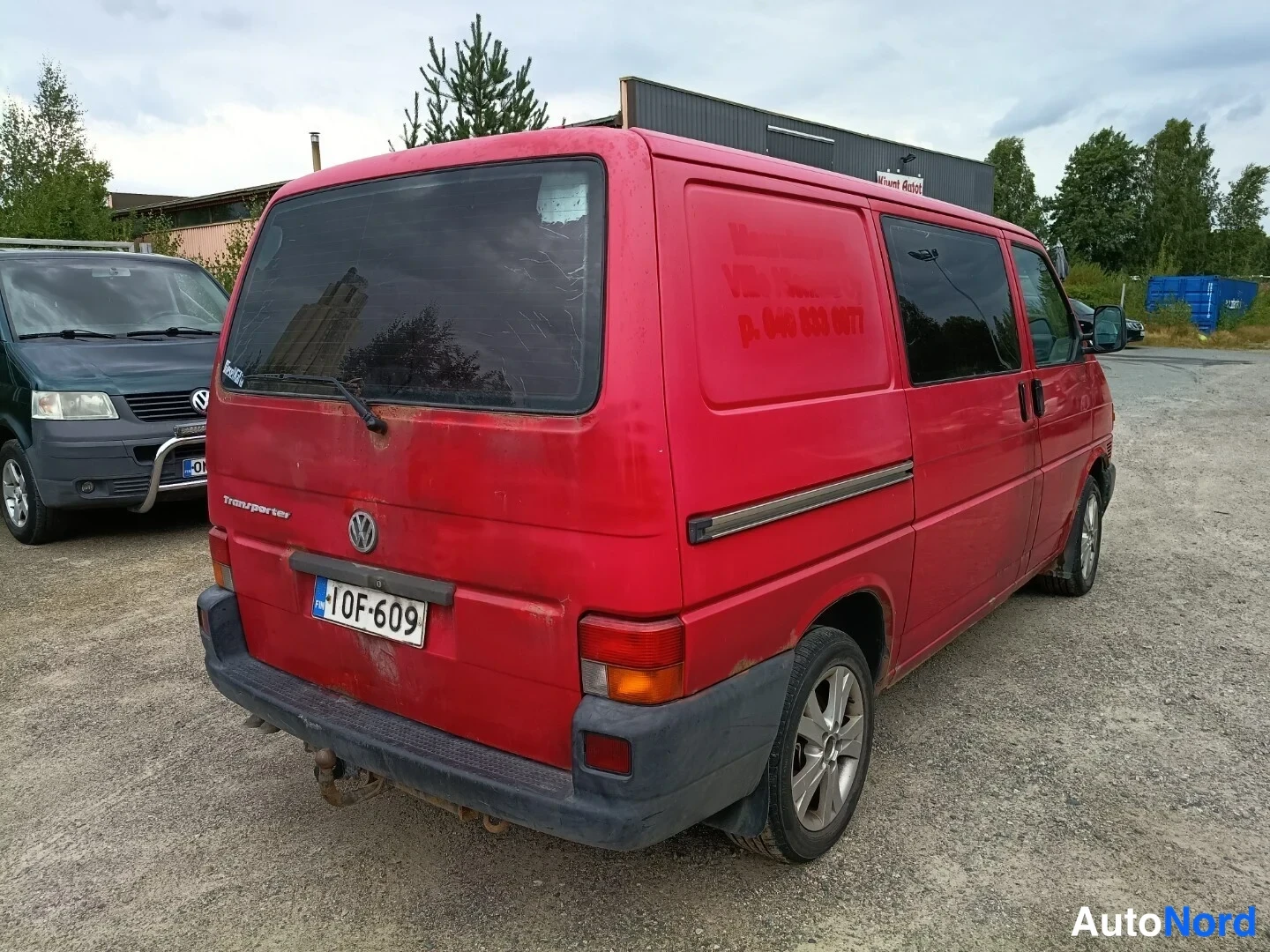 Takaviisto: Punaisen Volkswagen Transporterin takaosa ja sivu takaa viistosti kuvattuna; rekisterikilpi 10F-609 ja Volkswagen-merkki näkyvät takaluukussa.