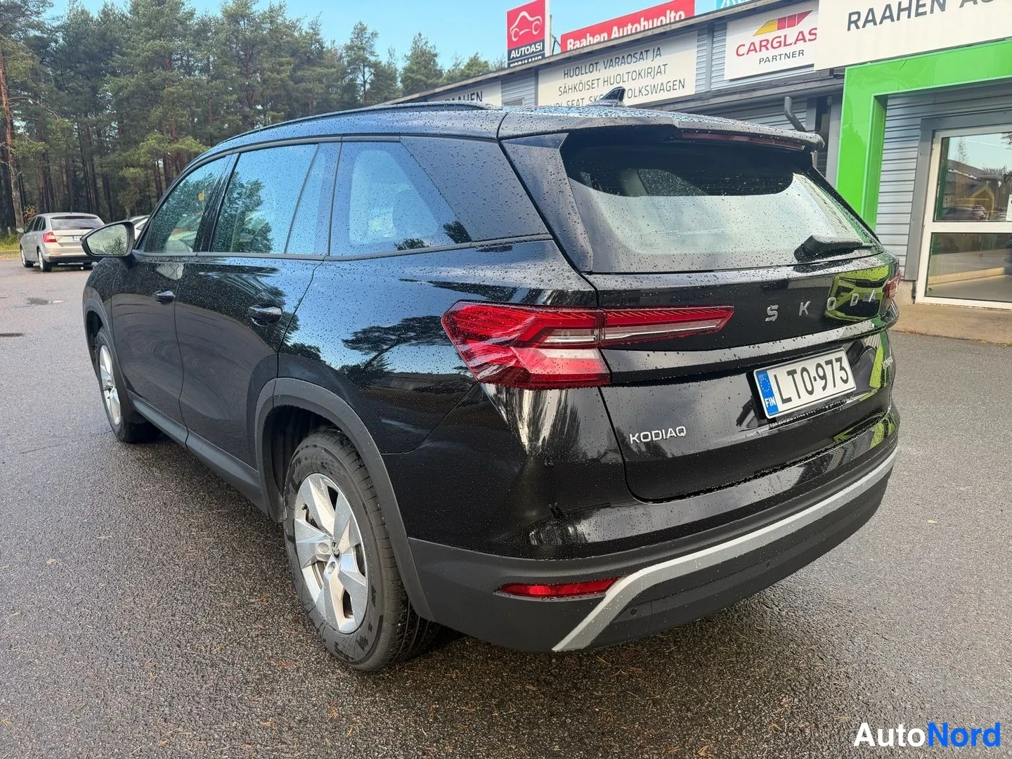 Takaviisto: Mustan Skoda Kodiaq -maasturin takakolmannes oikeasta takakulmasta, rekisteritunnus LT0-973, taustalla autoliike.
