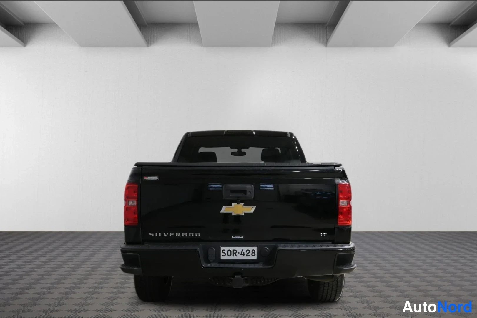 Takaa: Mustan Chevrolet Silverado -avolavan takanäkymä, rekisteritunnus ja Silverado-teksti näkyvät.