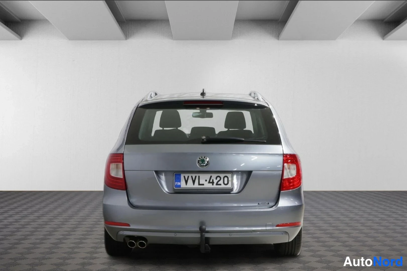 Takaa: Hopeanharmaan Skoda Superb -farmarin takaosa suoraan takaa kuvattuna, rekisterikilpi ja kaksi pakoputkea näkyvät.