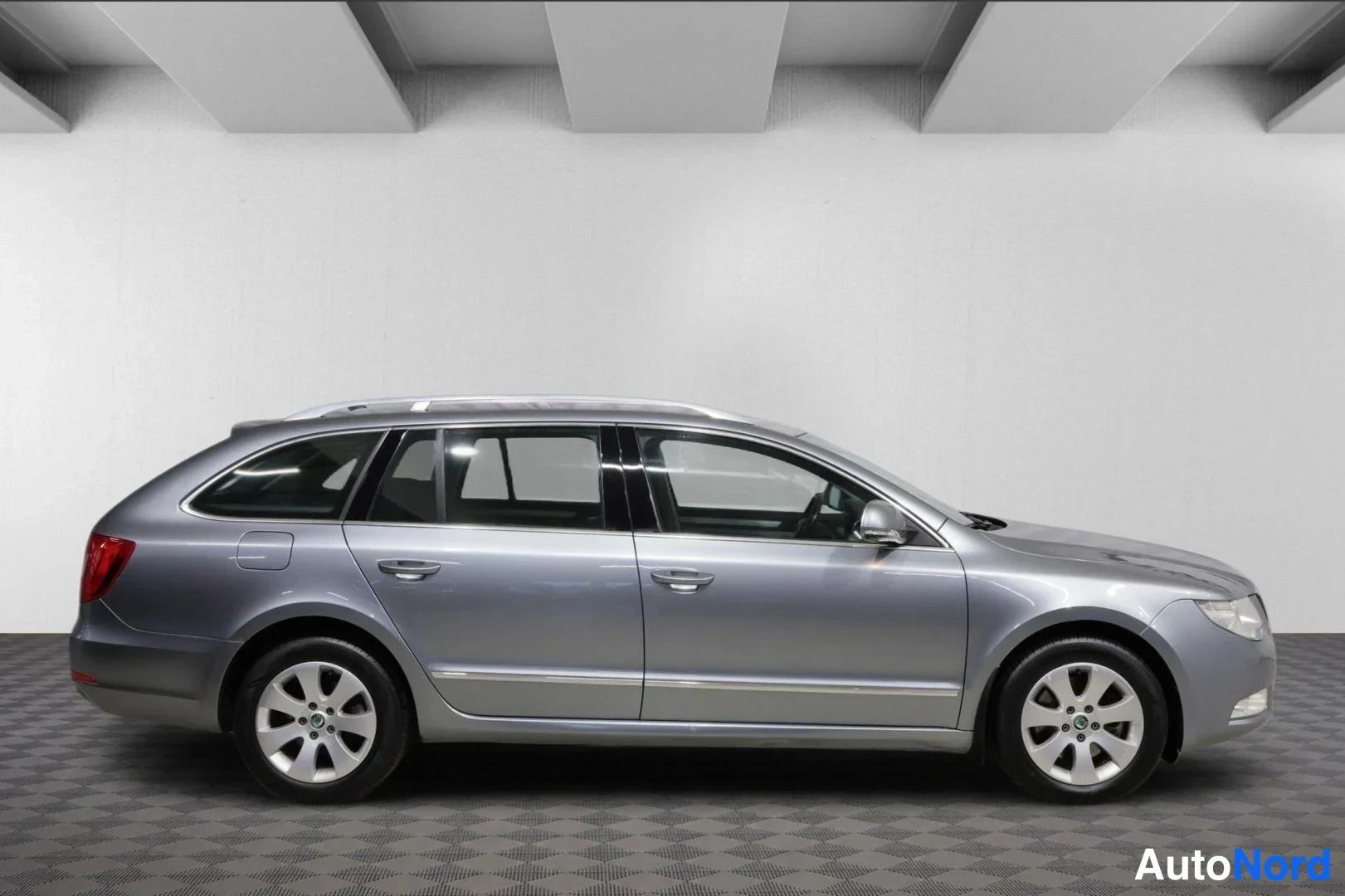 Sivulta: Skoda Superb -farmariauto sivulta, hopeaharmaa kori, kattokaiteet ja hopeavanteet.