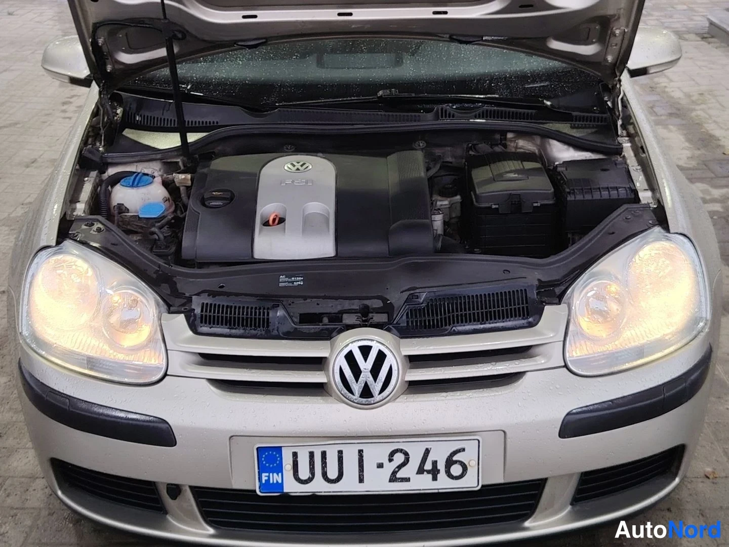 Edestä: Volkswagenin konepeitto auki: FSI-merkitty moottori, etusäteilijä ja rekisterikilpi, auton keula suoraan edestä valokuvattuna.